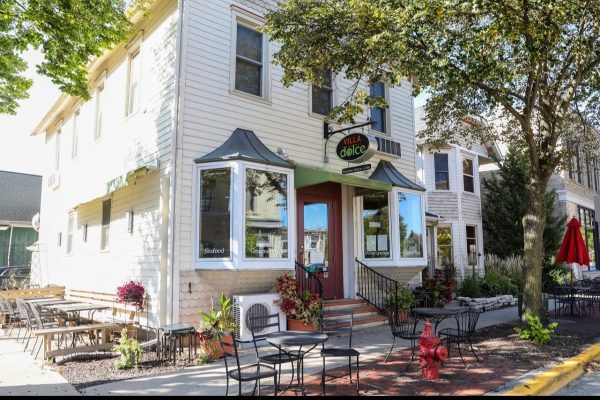 A restaurant with tables and chairs in front of it.