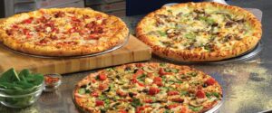 three pizzas sitting on top of a wooden cutting board