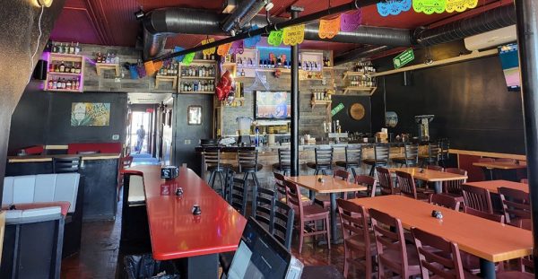 The inside of a mexican restaurant with tables and chairs.