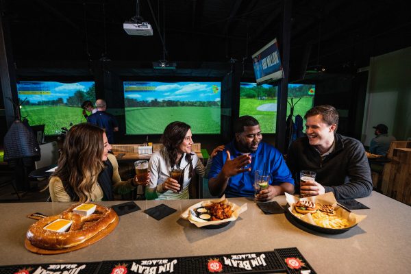 A group of people sitting at a table with food and drinks.