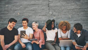 a group of people chatting and laughing all while looking at different electronic devices