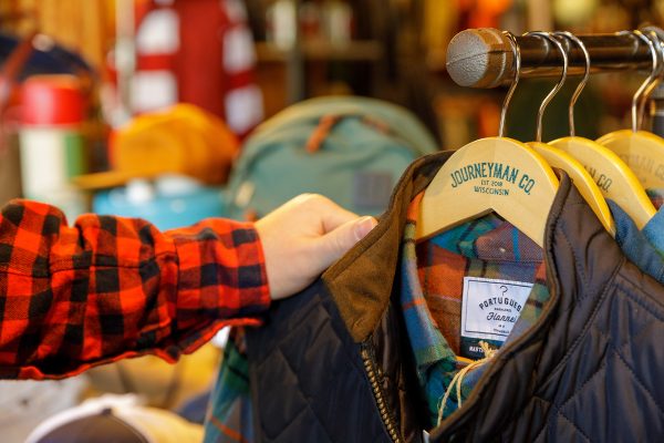 A person is holding a jacket on a rack.