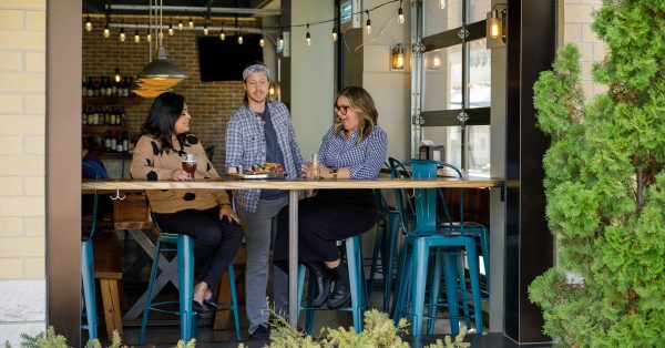 Three people sitting at a bar in a restaurant.