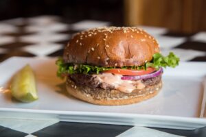 a hamburger on a plate with a pickle on the side