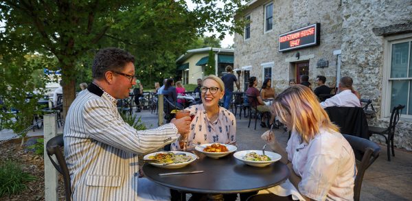 A group of people sitting at an outdoor table eating food.