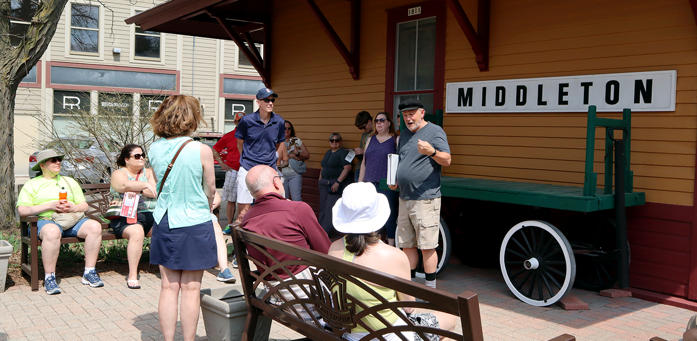 A group of people sitting on a bench in front of a train station.