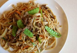 a white plate topped with noodles and vegetables