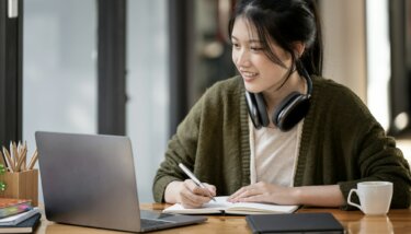 Woman taking notes at her computer as she learns how to launch a membership site.